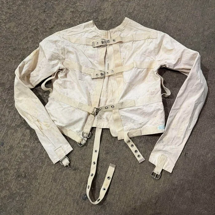 An old, canvas straitjacket with buckles and straps, a rare find hitting the jackpot at a thrift store.