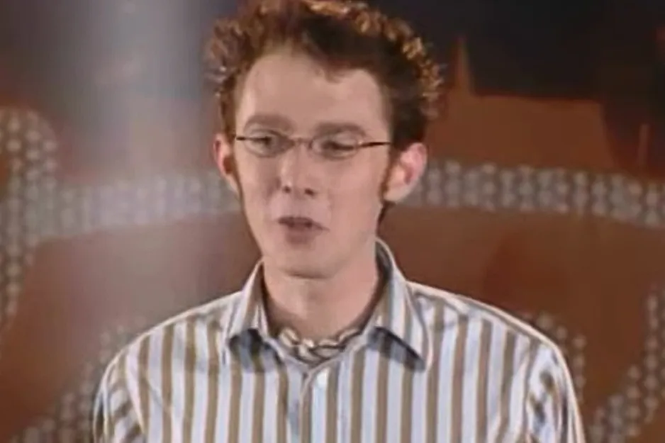 Clay Aiken, a memorable participant in American Idol, with glasses and a striped shirt.