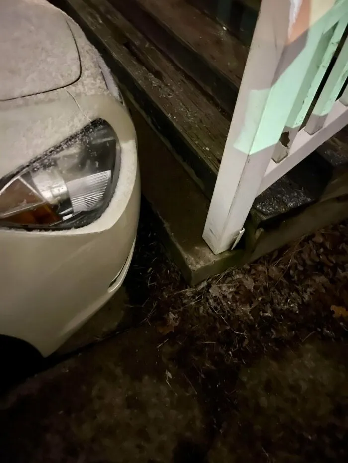 A white car parked extremely close to a snowy porch, highlighting bad parking by jerk neighbors.