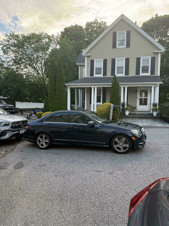 A car parked poorly, blocking a driveway and showing jerk neighbors parking issues.