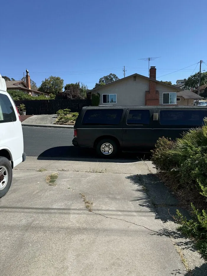 A large black vehicle poorly parked, blocking a driveway, illustrating issues with jerk neighbors and their parking.