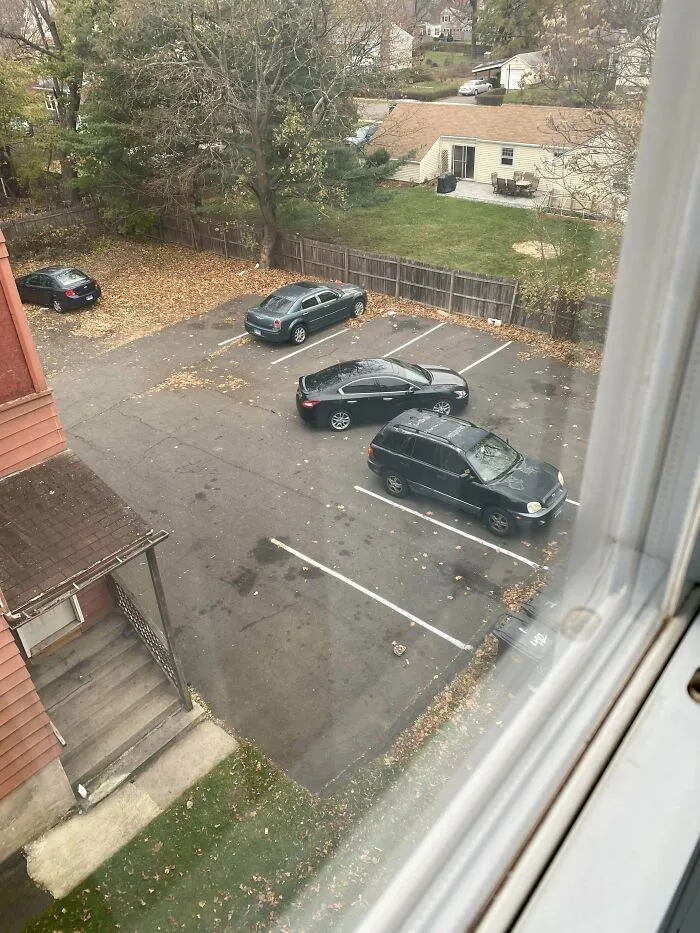 An aerial view of a parking lot where several jerk neighbors cars are poorly parked across multiple spaces.