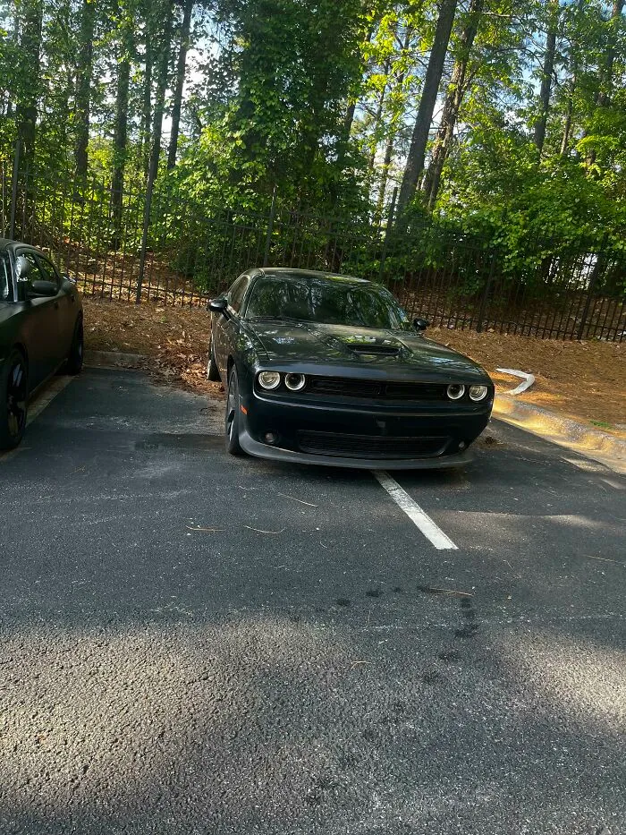 A black car poorly parked, taking up two parking spots, an example of jerk neighbors parking.