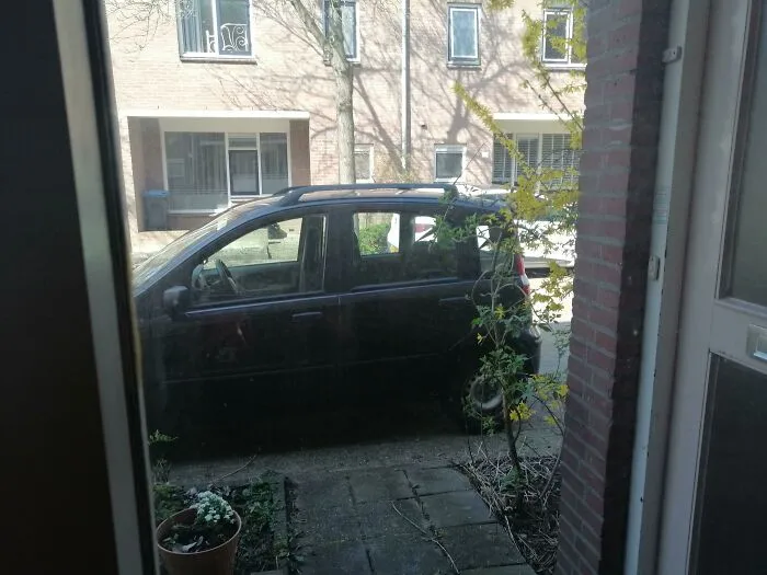 A black car parked directly in front of a door, showing bad parking by neighbors.