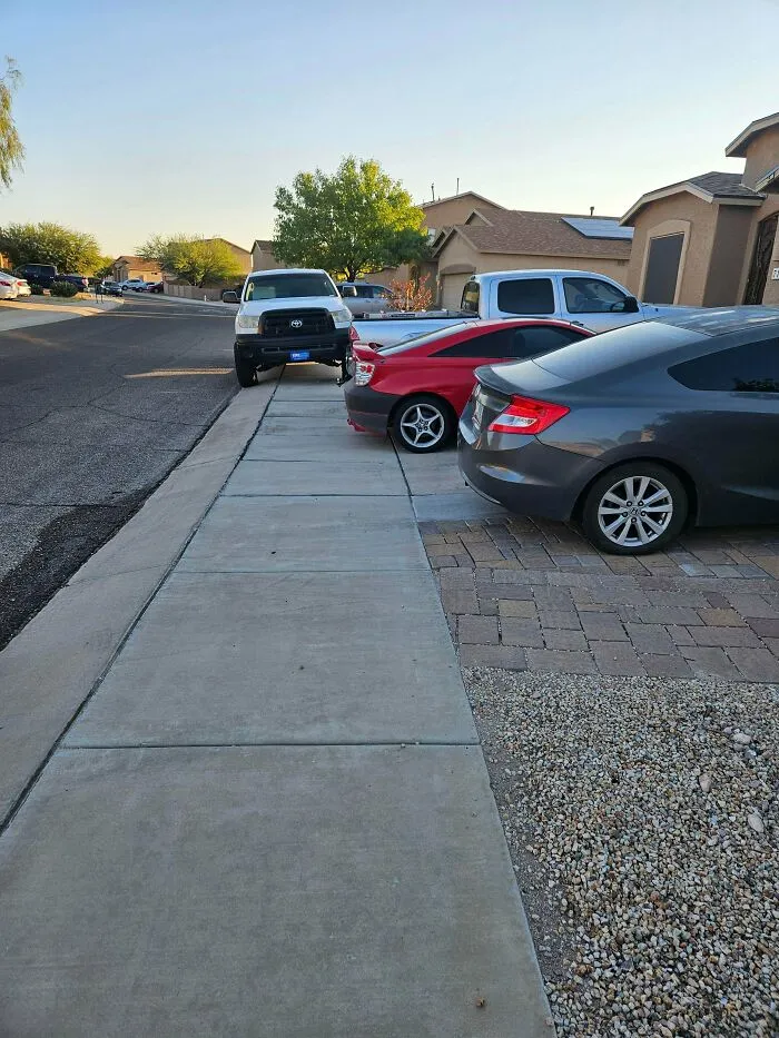 A white truck poorly parked on a sidewalk, obstructing pedestrian access, showing bad parking neighbors.