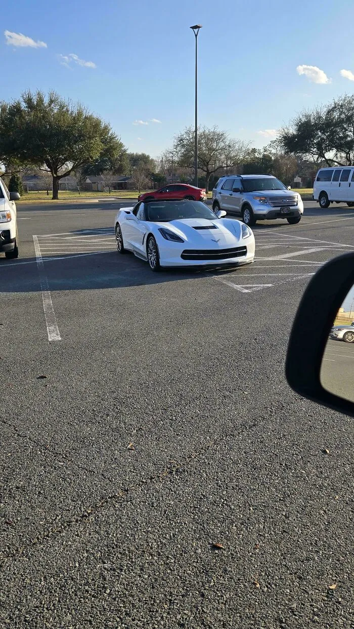 A white sports car parked diagonally, occupying multiple parking spaces, a prime example of jerk neighbors' parking.