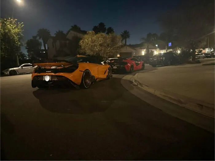Luxury sports cars in an urgent parking lesson, parked closely together on a residential street at night.