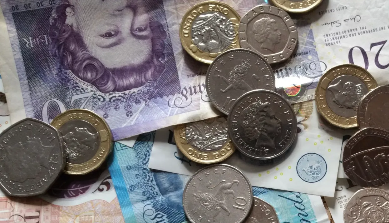 Various UK currency notes and coins, including pounds, pence, and other denominations.