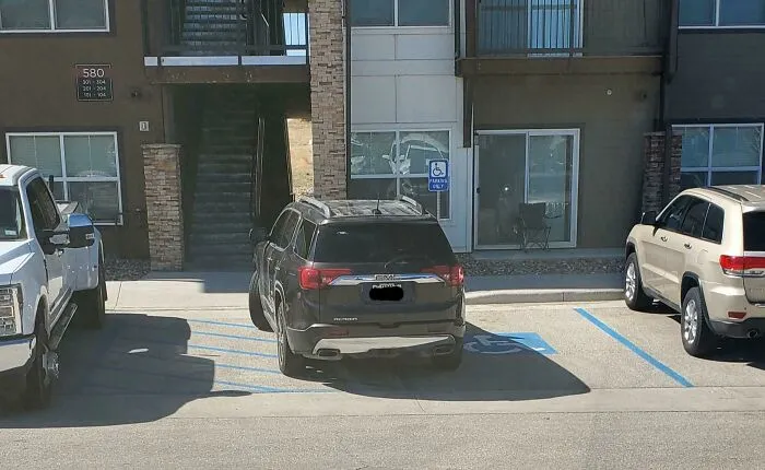 A black SUV poorly parked across two disabled parking spaces, showing a lack of common sense and parking etiquette.