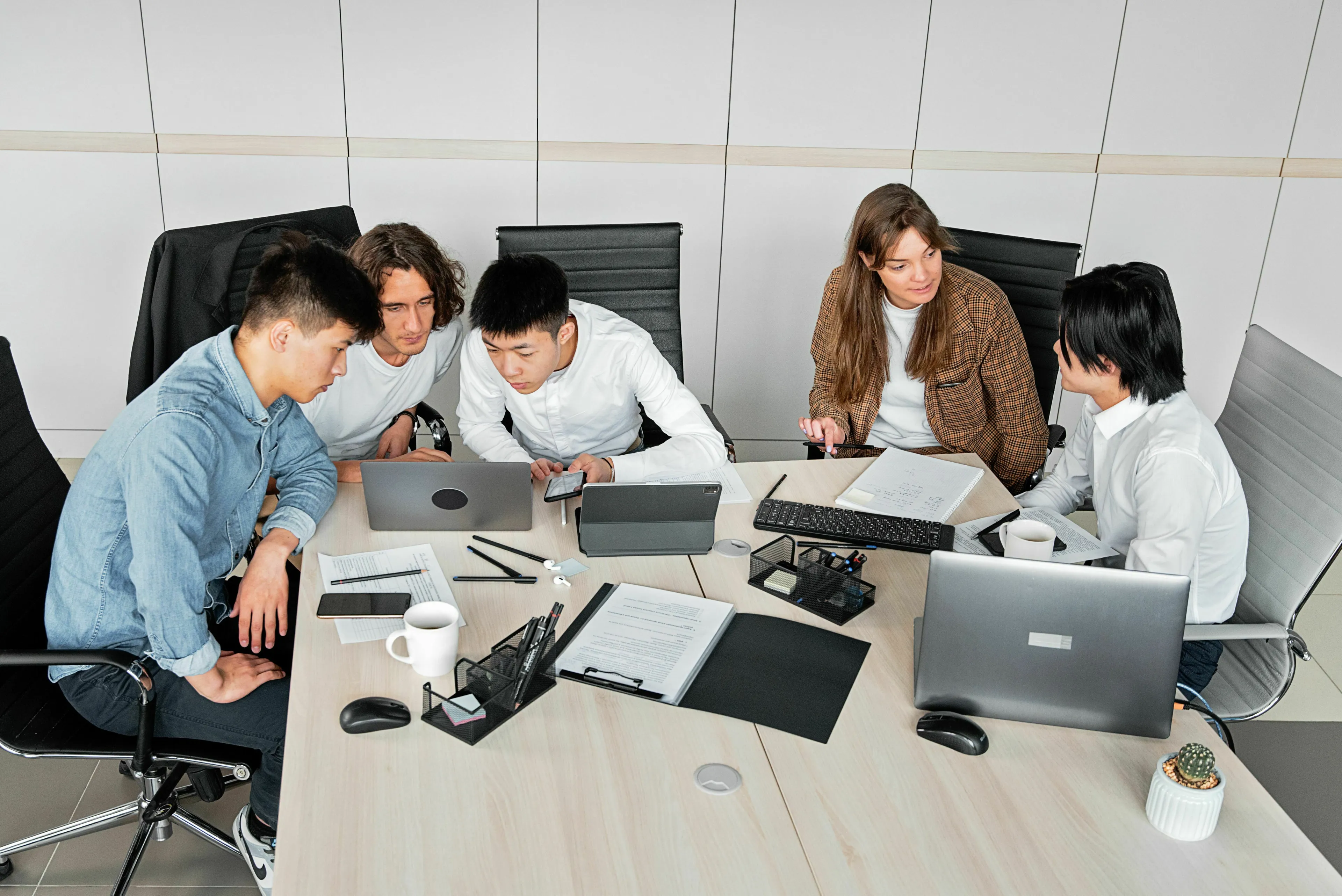 A diverse group of five young people working on a group project around a table with laptops, to assess what kind of liar you are.