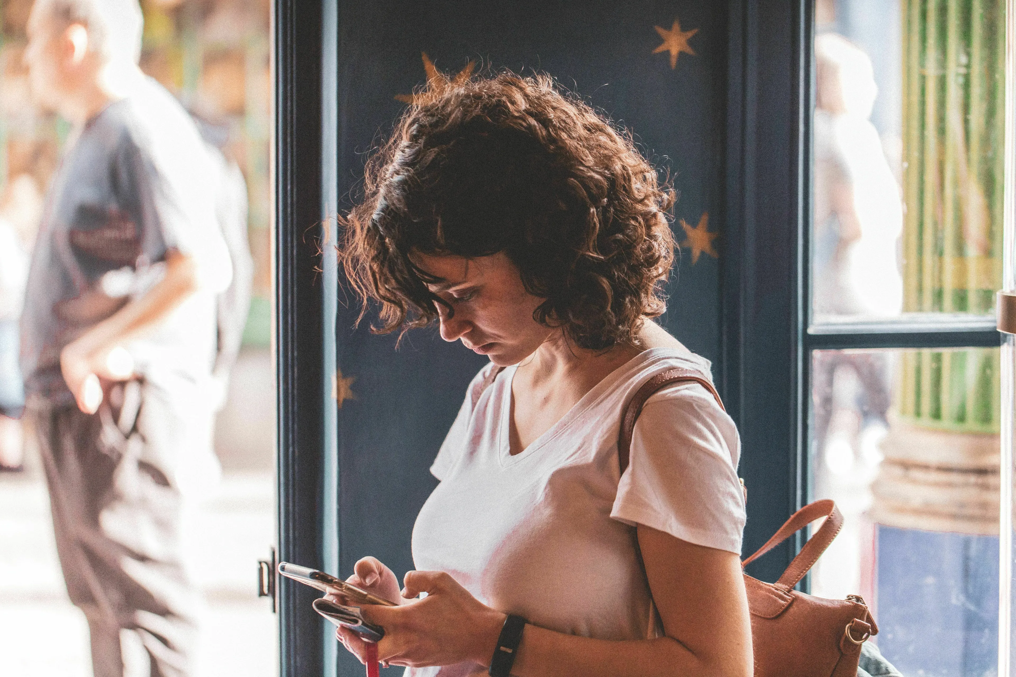 A woman is deeply engrossed in her phone, composing a go-to text for canceling plans.