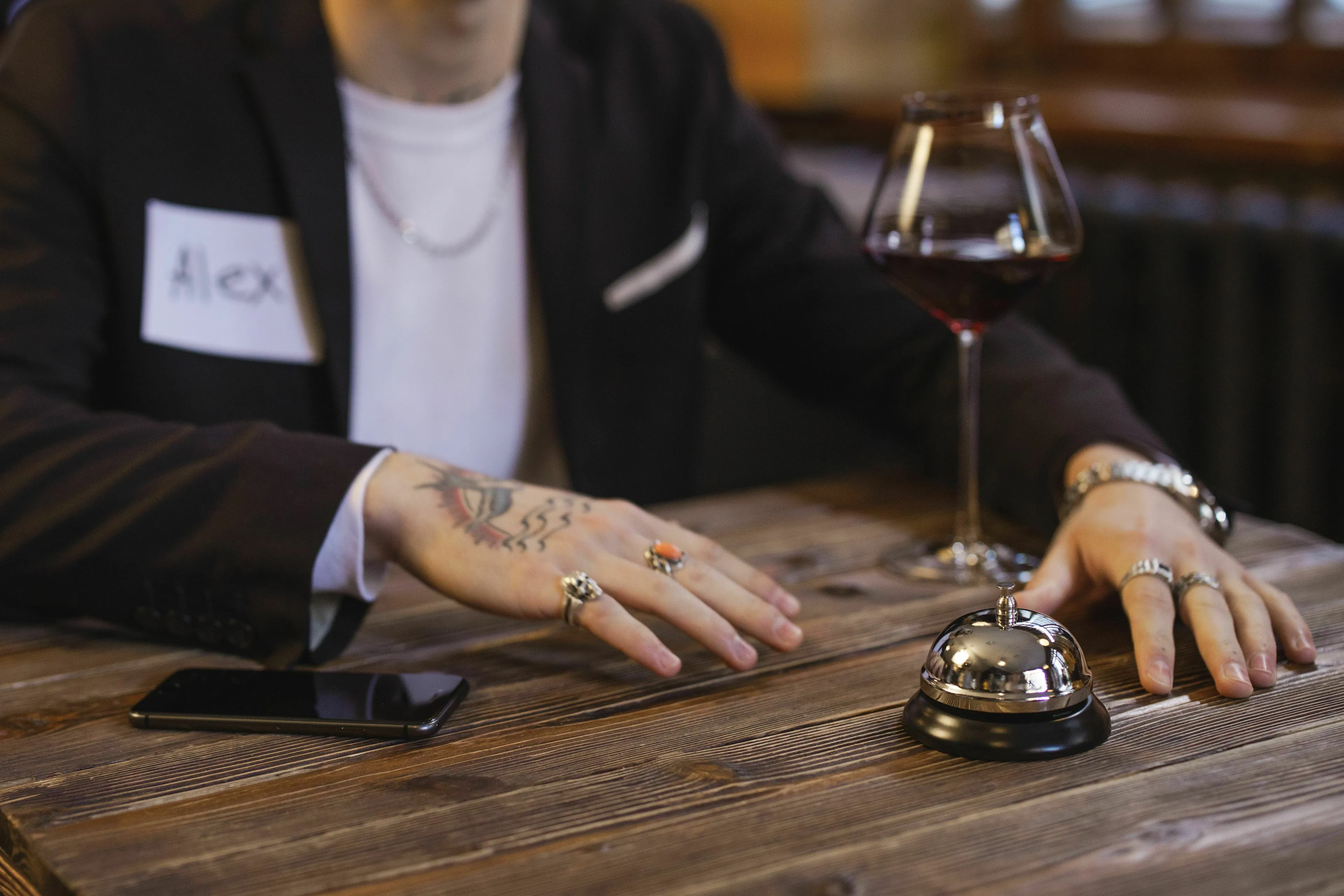 A man named Alex on a bad blind date, his hands resting on the table with a drink.