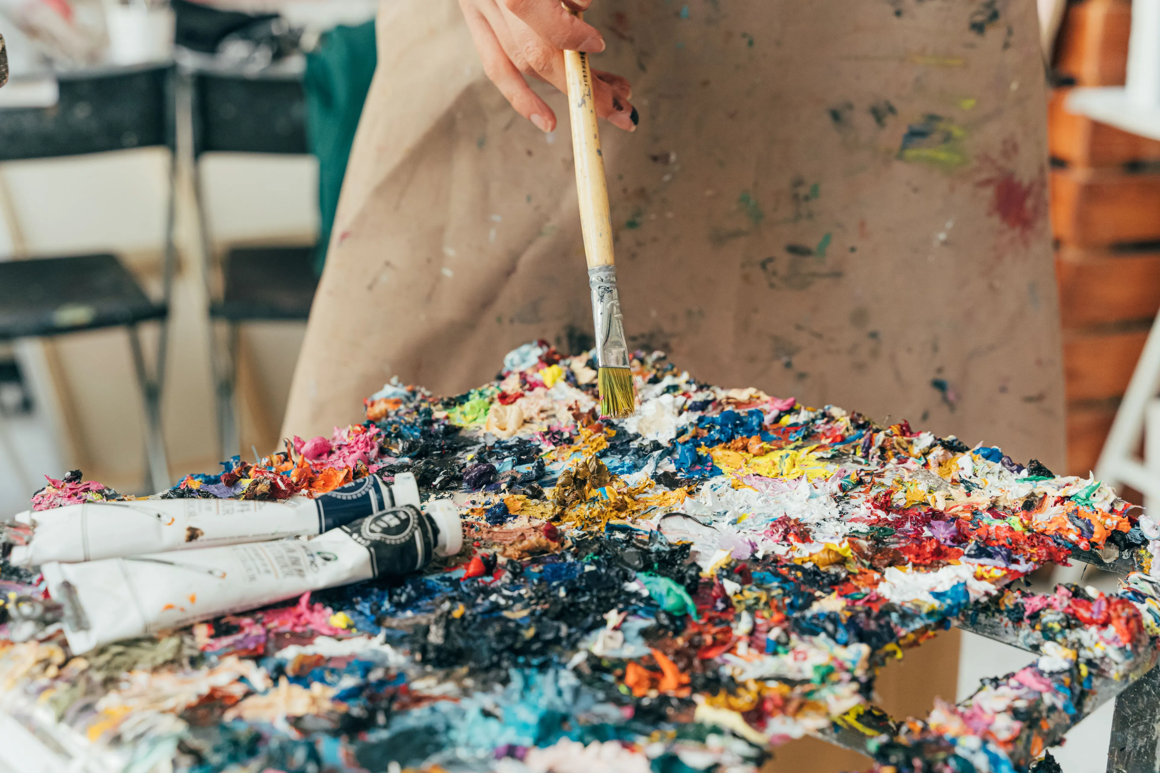 A person painting with a brush on a canvas covered in colorful paint, representing a hobby one might lie about.
