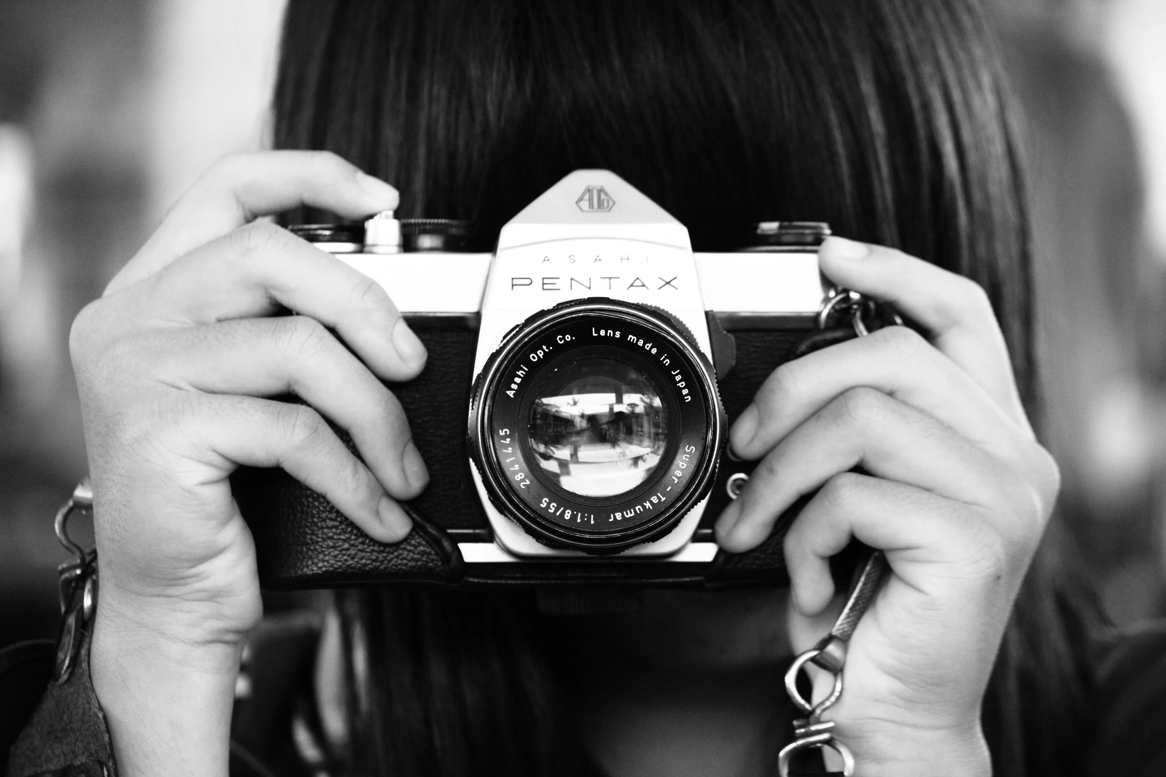Black and white image of a person holding an old film camera, focused on photography as a hobby.