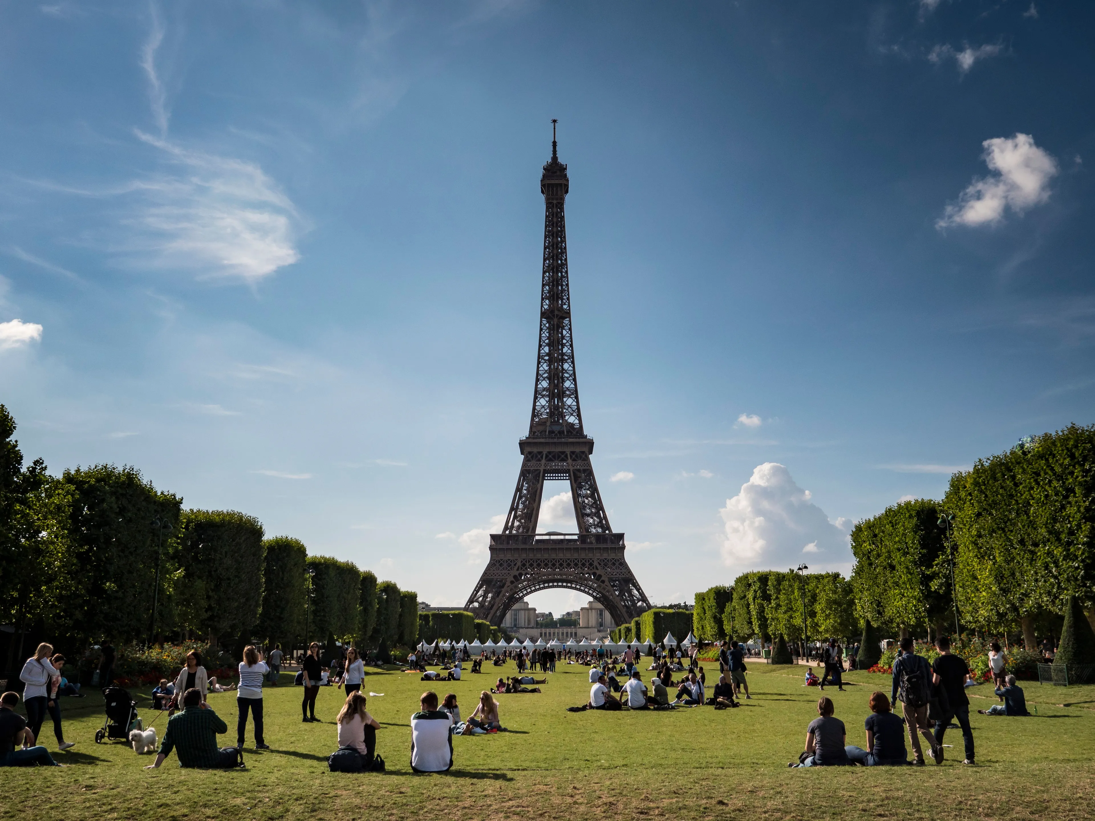 The Eiffel Tower stands tall in Paris, with people relaxing on the grass below, perfect for a landmark you'd exaggerate visiting.