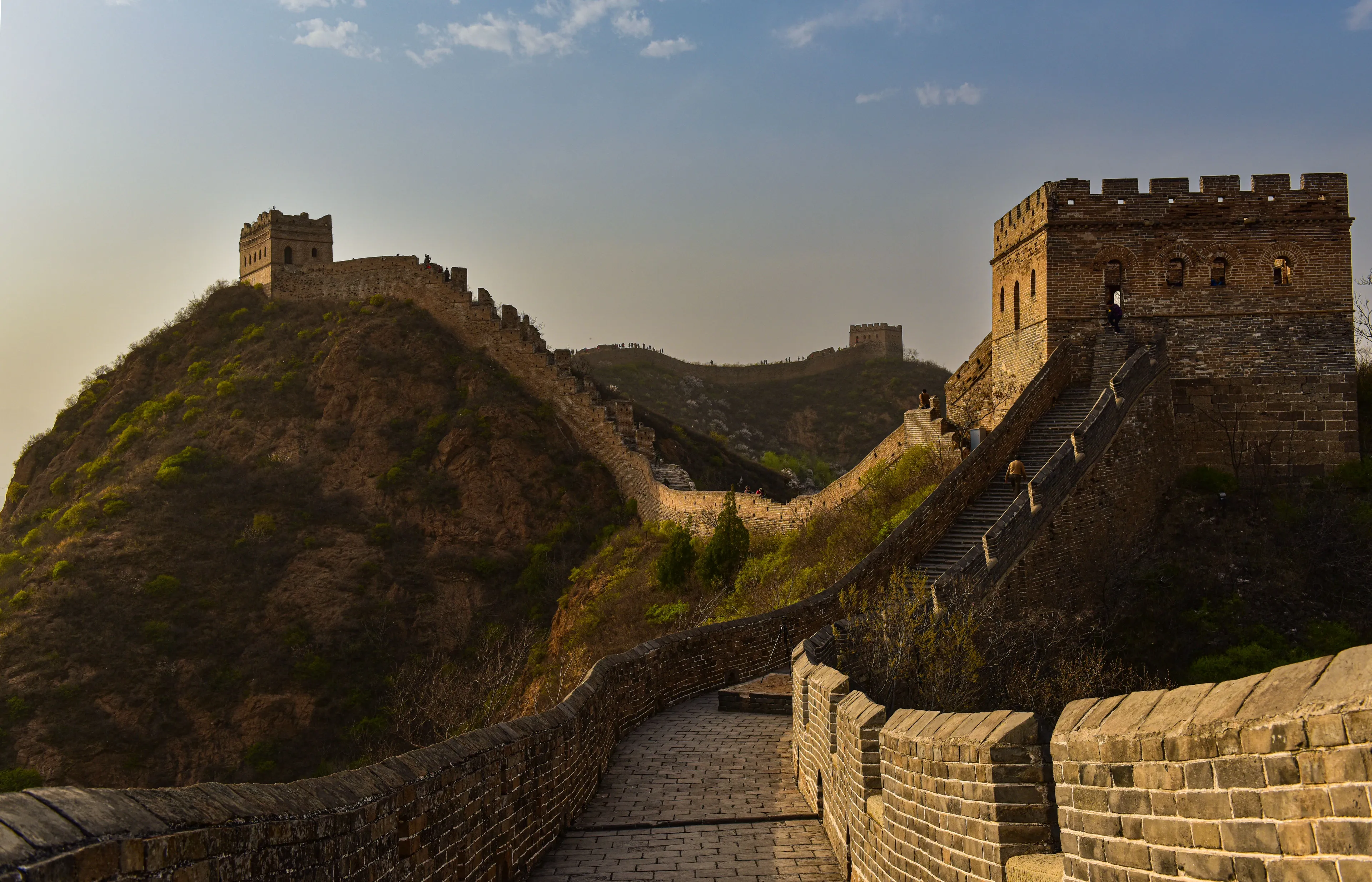 The Great Wall of China stretches across rolling hills under a clear sky, an iconic landmark you'd exaggerate visiting.