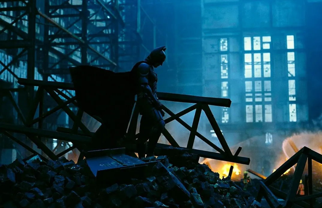 Batman stands amidst rubble and fire, symbolizing Batman's distinct lying style.