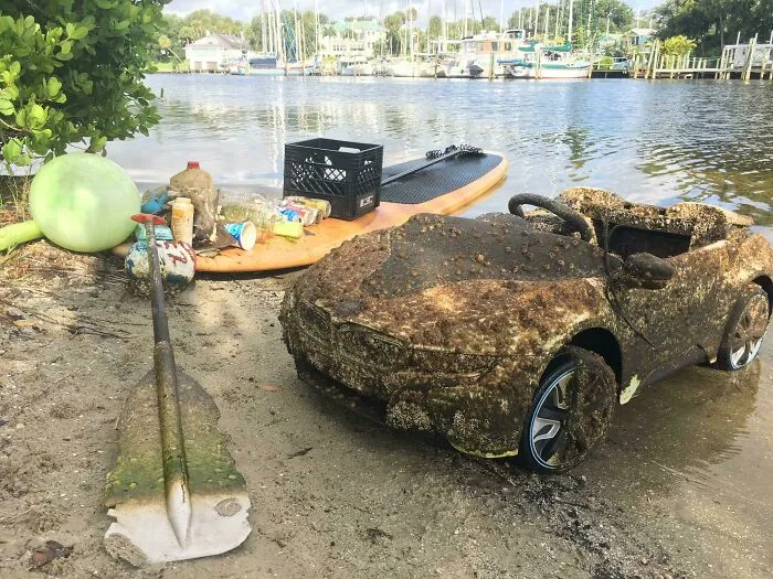 A dirty child's car and various trash items polluting a body of water, showing trash taking over the world.