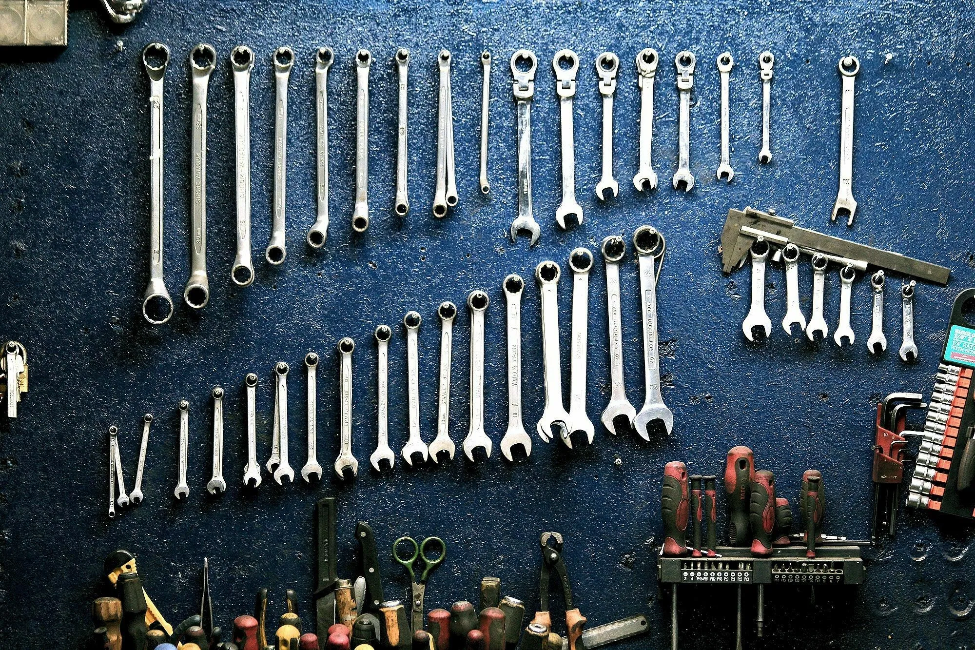 Wrenches and tools hanging on a blue wall, representing essential tools in a Renaissance workshop.