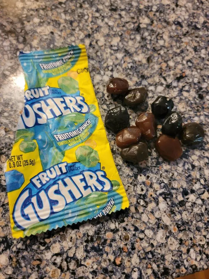 Old products: A bag of Fruit Gushers and a pile of gushers on a speckled countertop.
