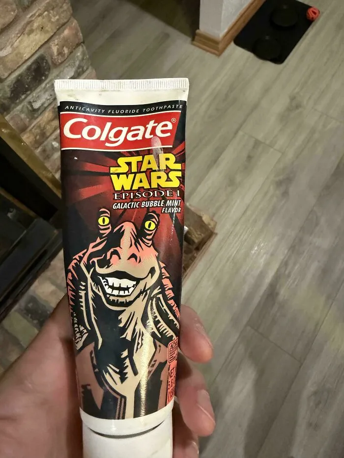 A hand holding old products: Colgate Star Wars Episode I toothpaste featuring Jar Jar Binks.