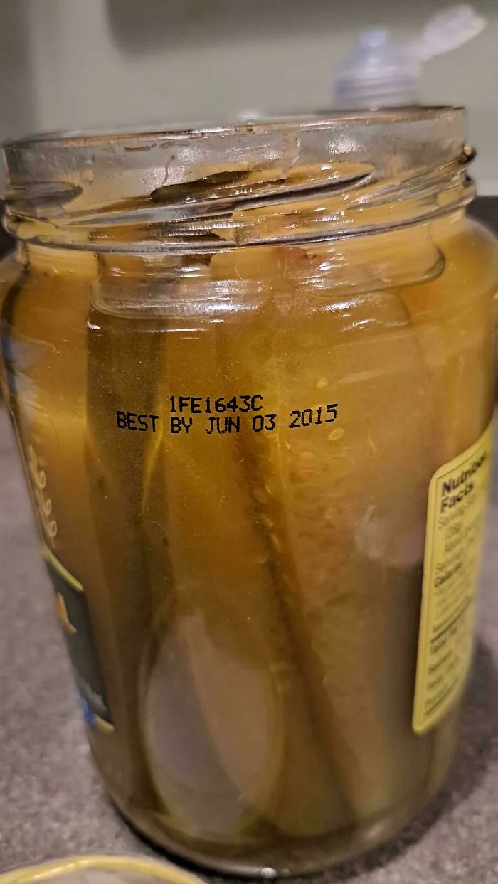 A jar of pickles with an expired best by date of June 03, 2015, among old products.