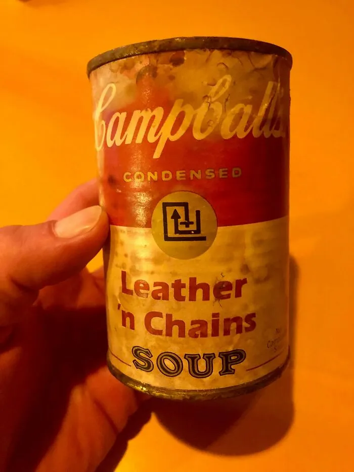 A hand holding a can of Campbells condensed Leather n Chains Soup, an example of old products people found at home.