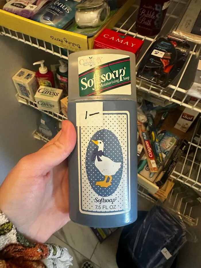 A hand holding an old Softsoap bottle with a duck design, part of a collection of old products.