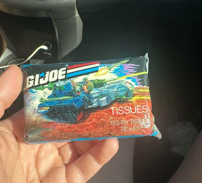 A hand holding a vintage G.I. Joe themed pack of tissues, an old product found at home.