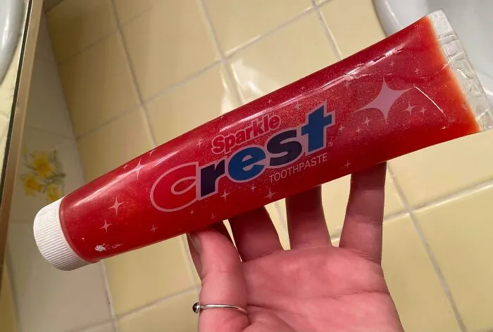 A hand holding a vintage Sparkle Crest Toothpaste tube, a classic old product found at home.