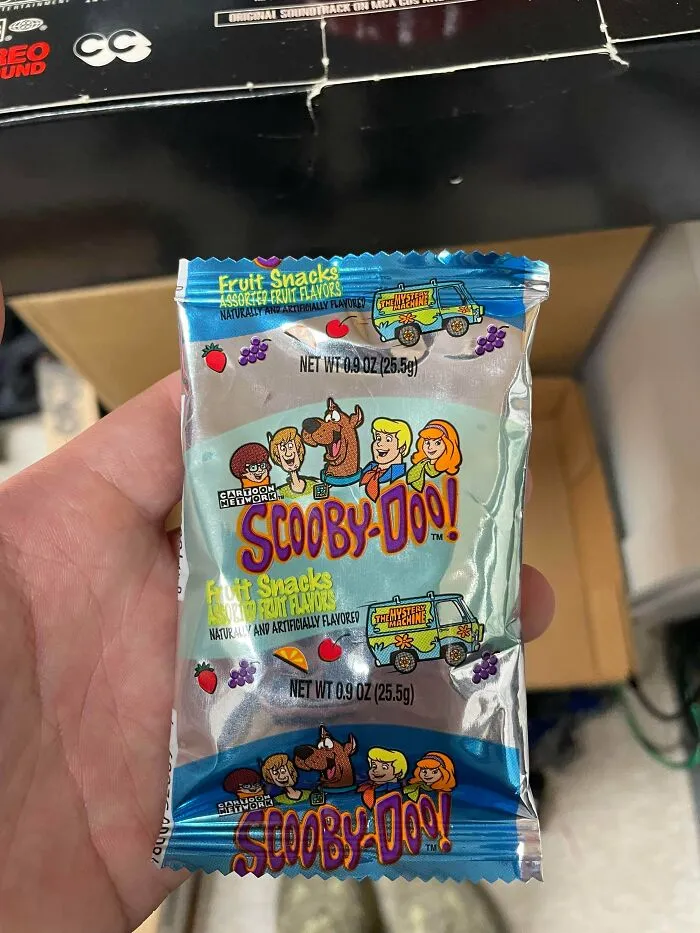 A hand holding a package of Scooby-Doo! fruit snacks, an old product found at home.