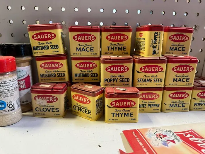A shelf full of various Sauer's spices, an array of old products found at home.