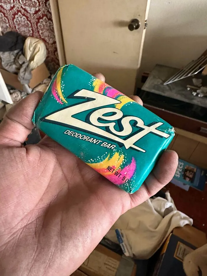 A hand holds an old bar of Zest deodorant soap, an old product found at home.