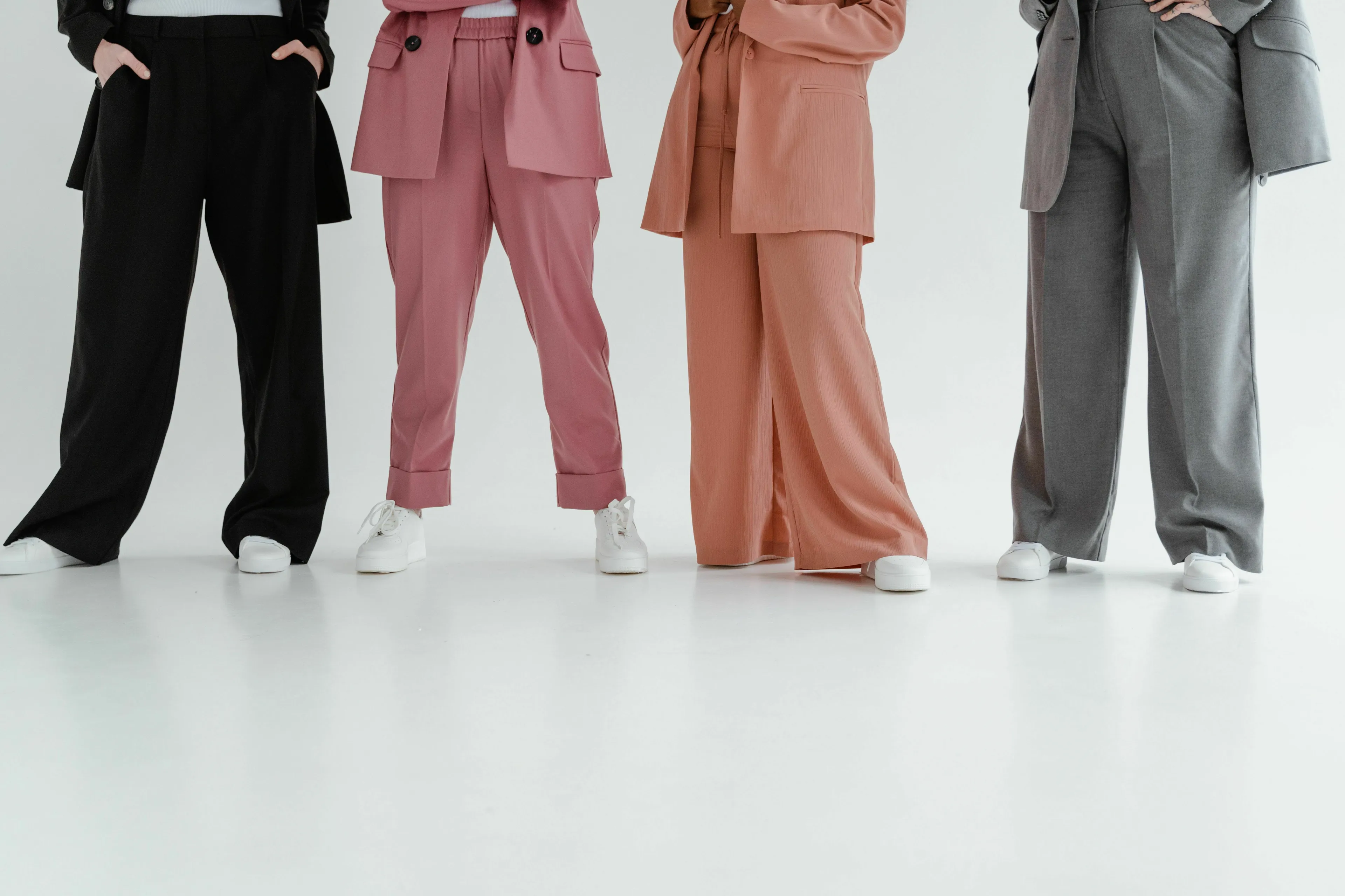 Four individuals showcasing different colored trousers, exploring American vs British English words.