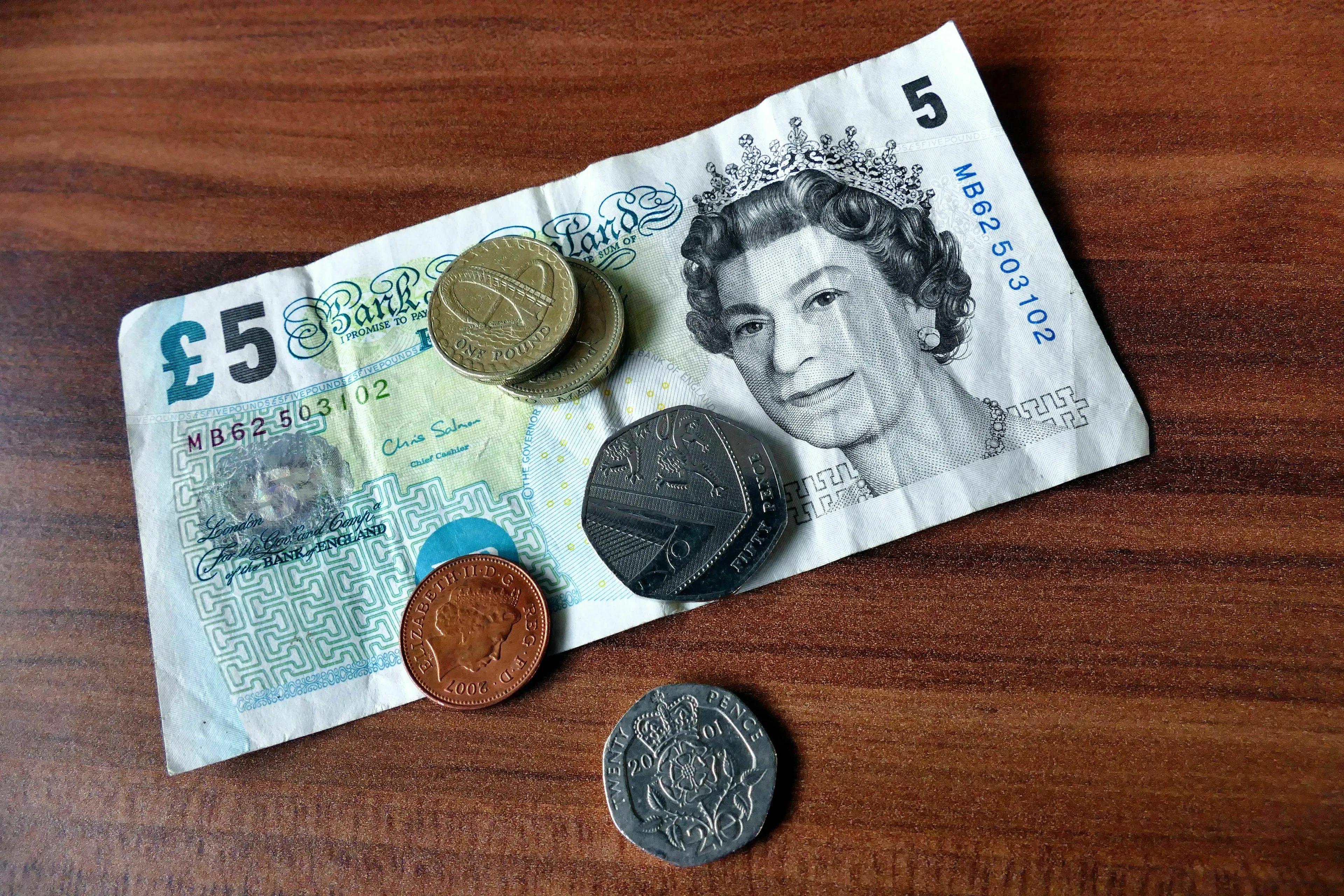 British money, including a five-pound note and various coins, representing British English words for currency.