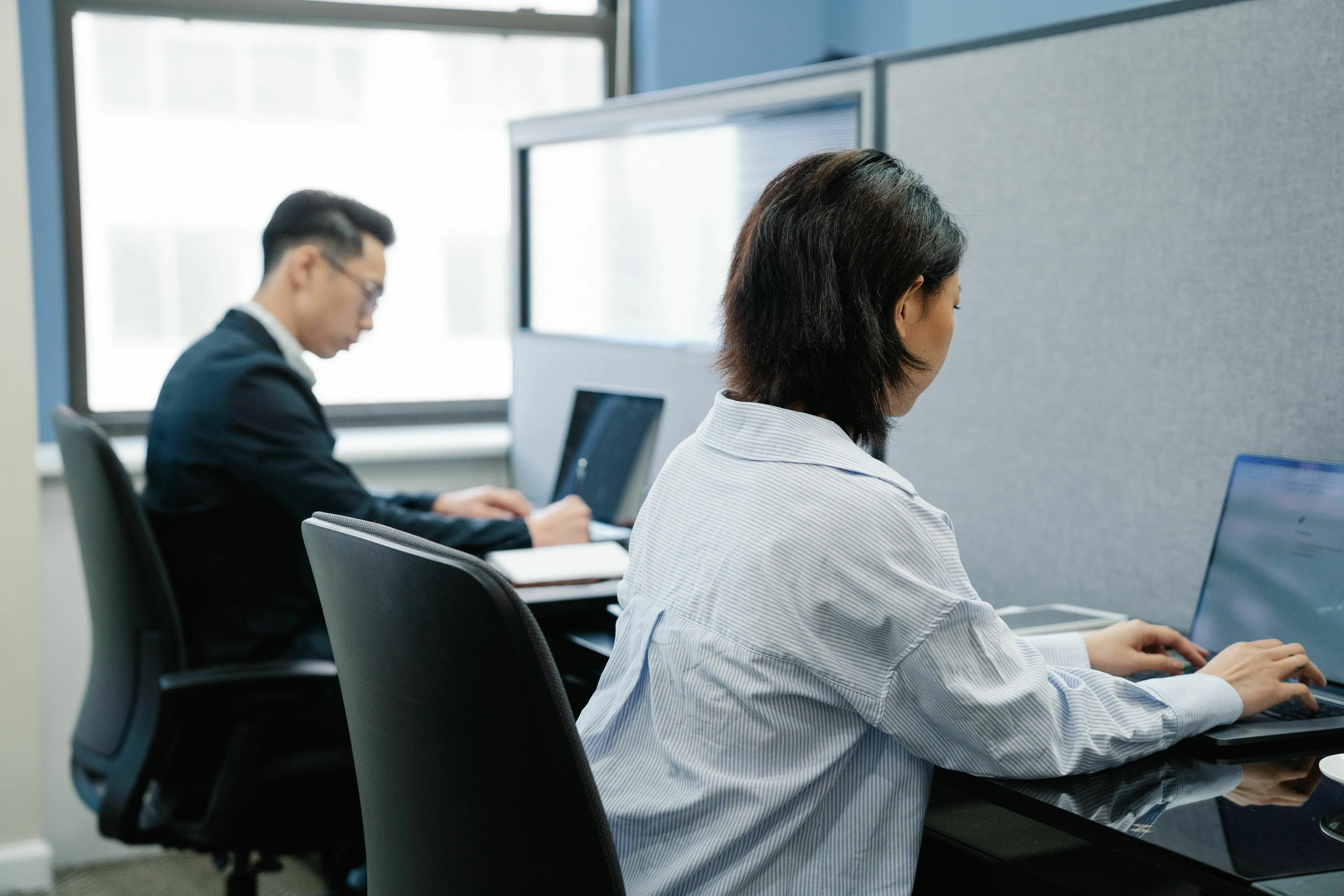Two people working on laptops in an office, symbolizing picking a job you'd want in this new world.