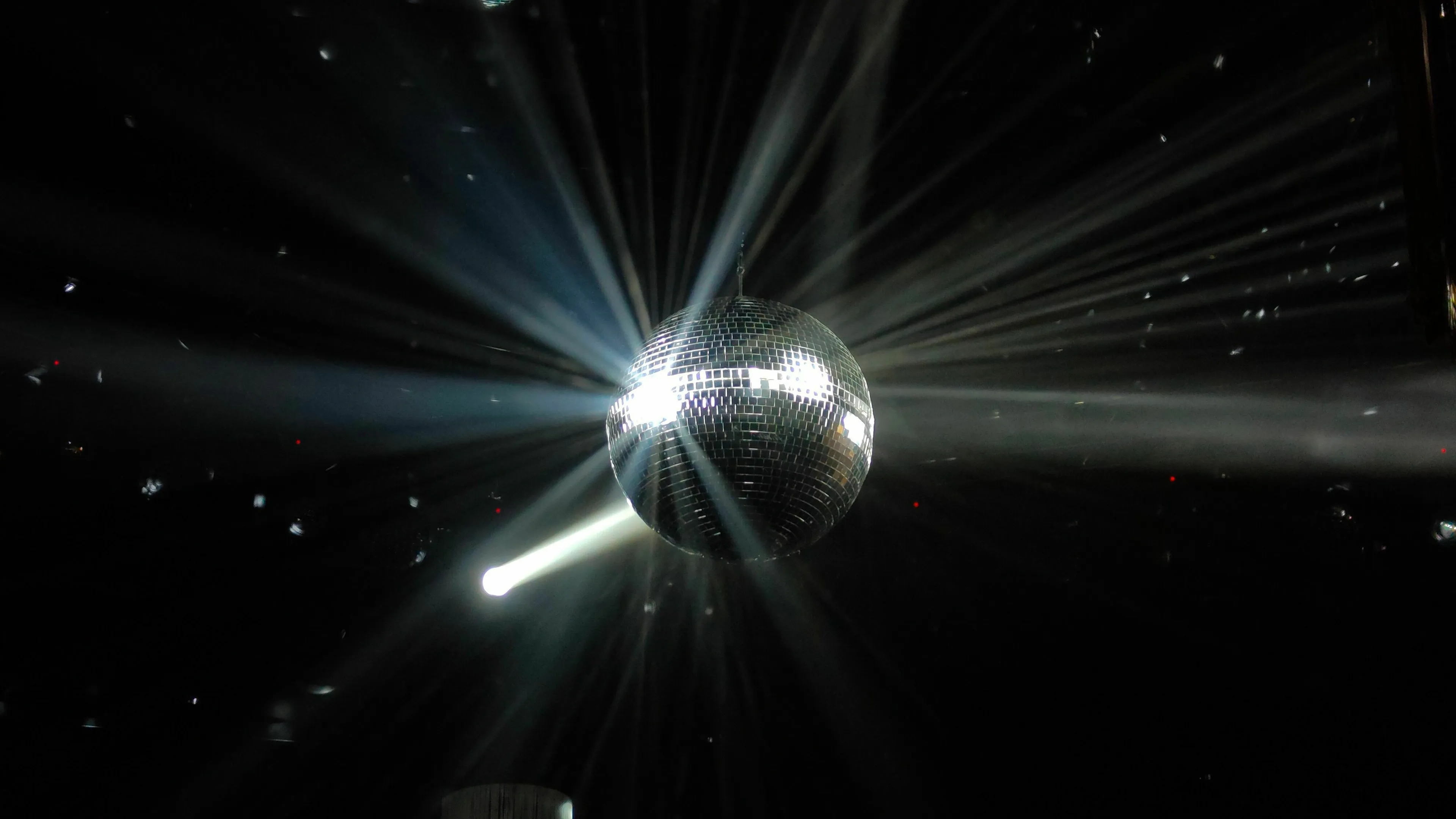 A disco ball with light beams, illustrating an ideal Friday night in this new dystopia.