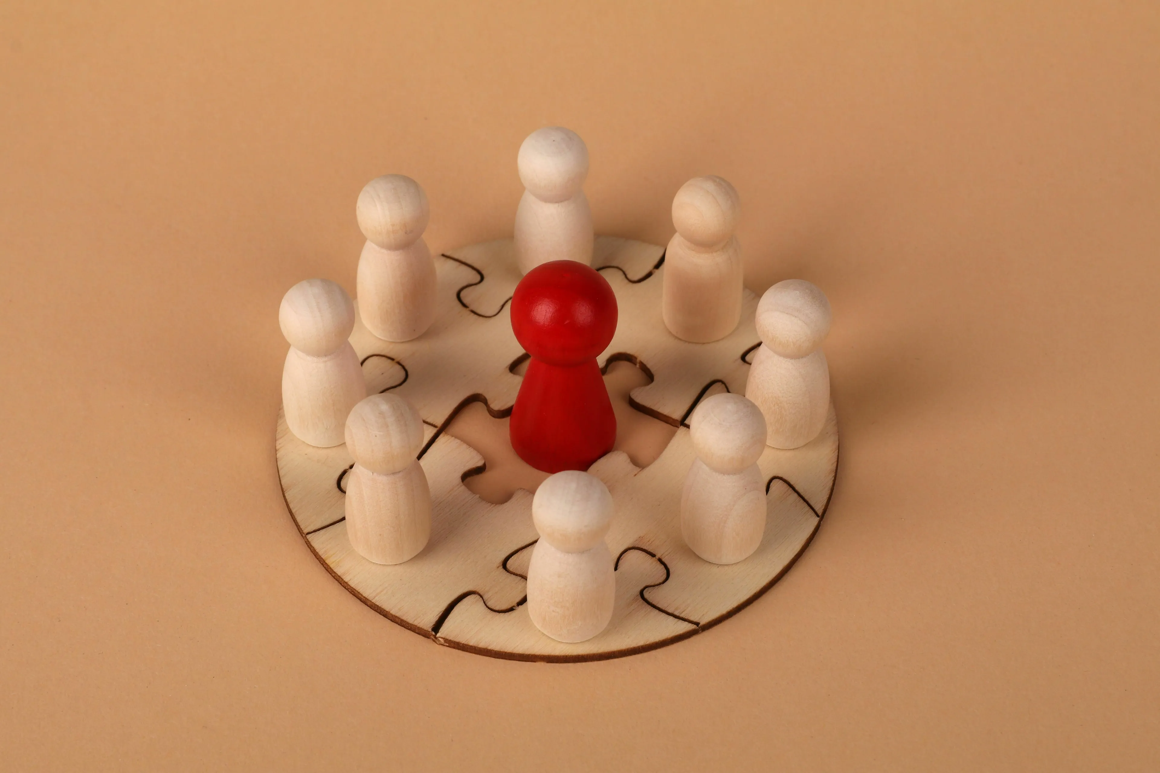 A red pawn surrounded by white pawns on a puzzle, depicting an ideal leader in a new world.
