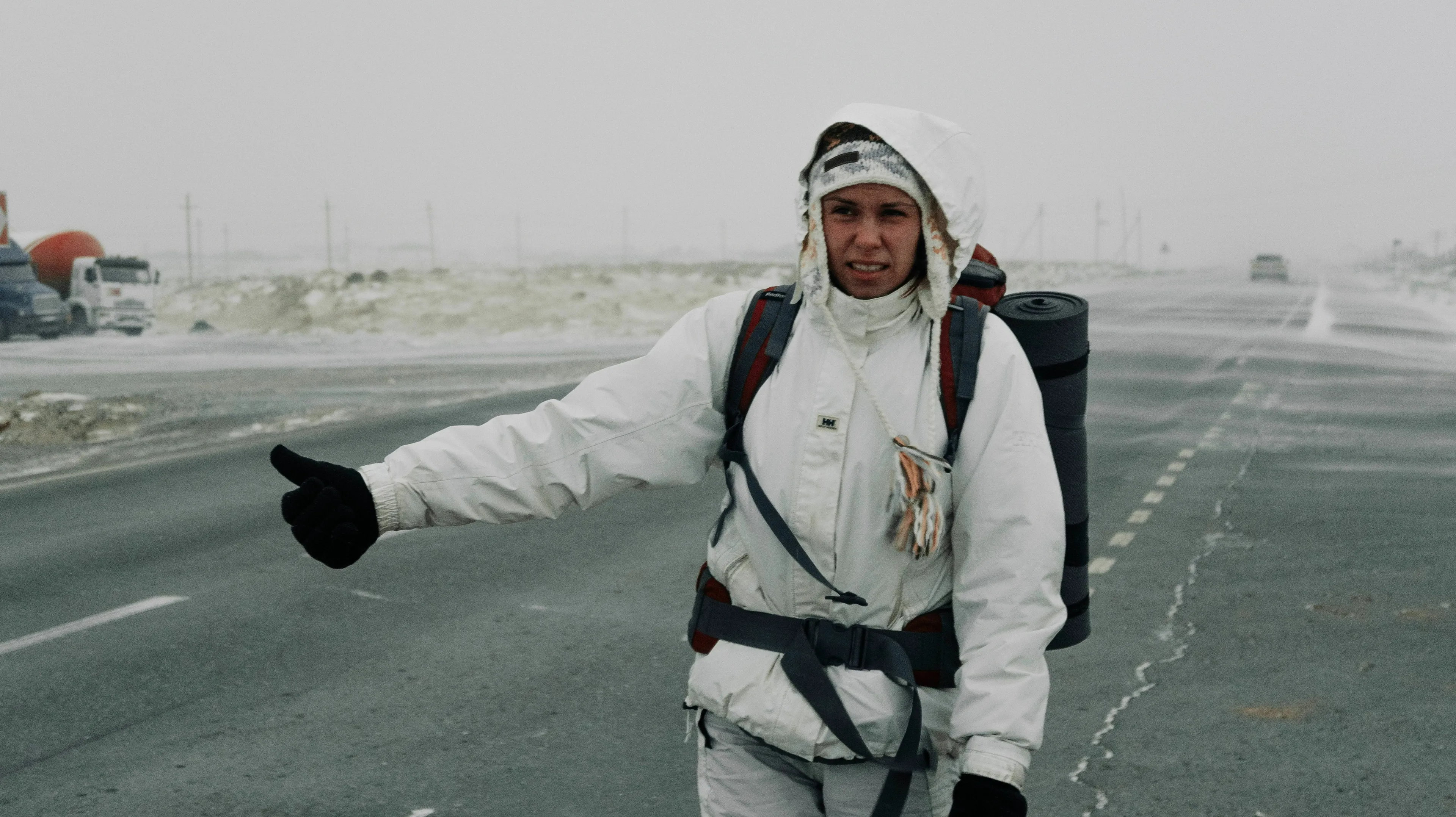 A stranger arrives asking for shelter, a person hitchhiking on a desolate road in winter.