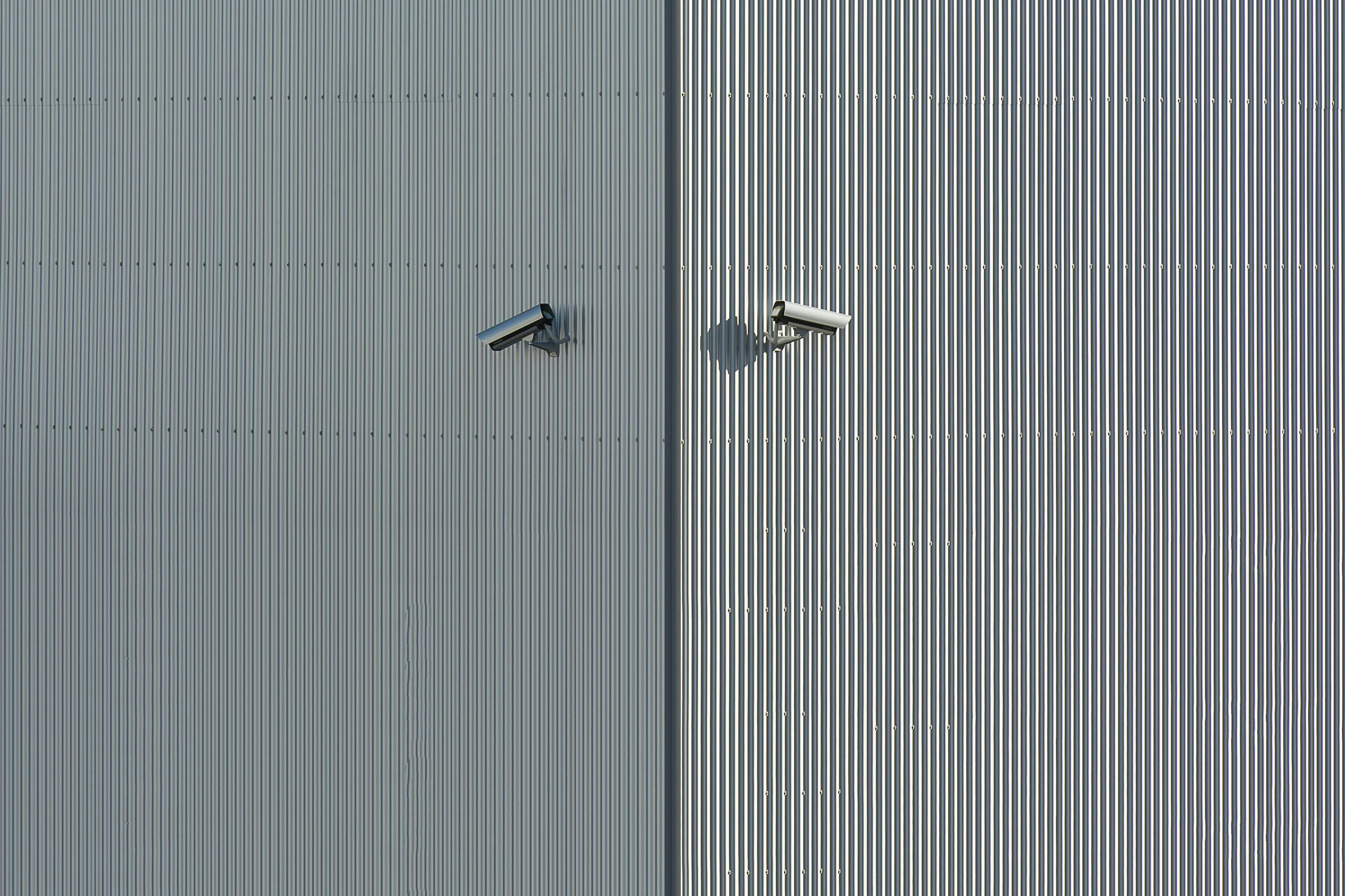Surveillance for everyone's safety, two security cameras mounted on a corrugated metal wall.