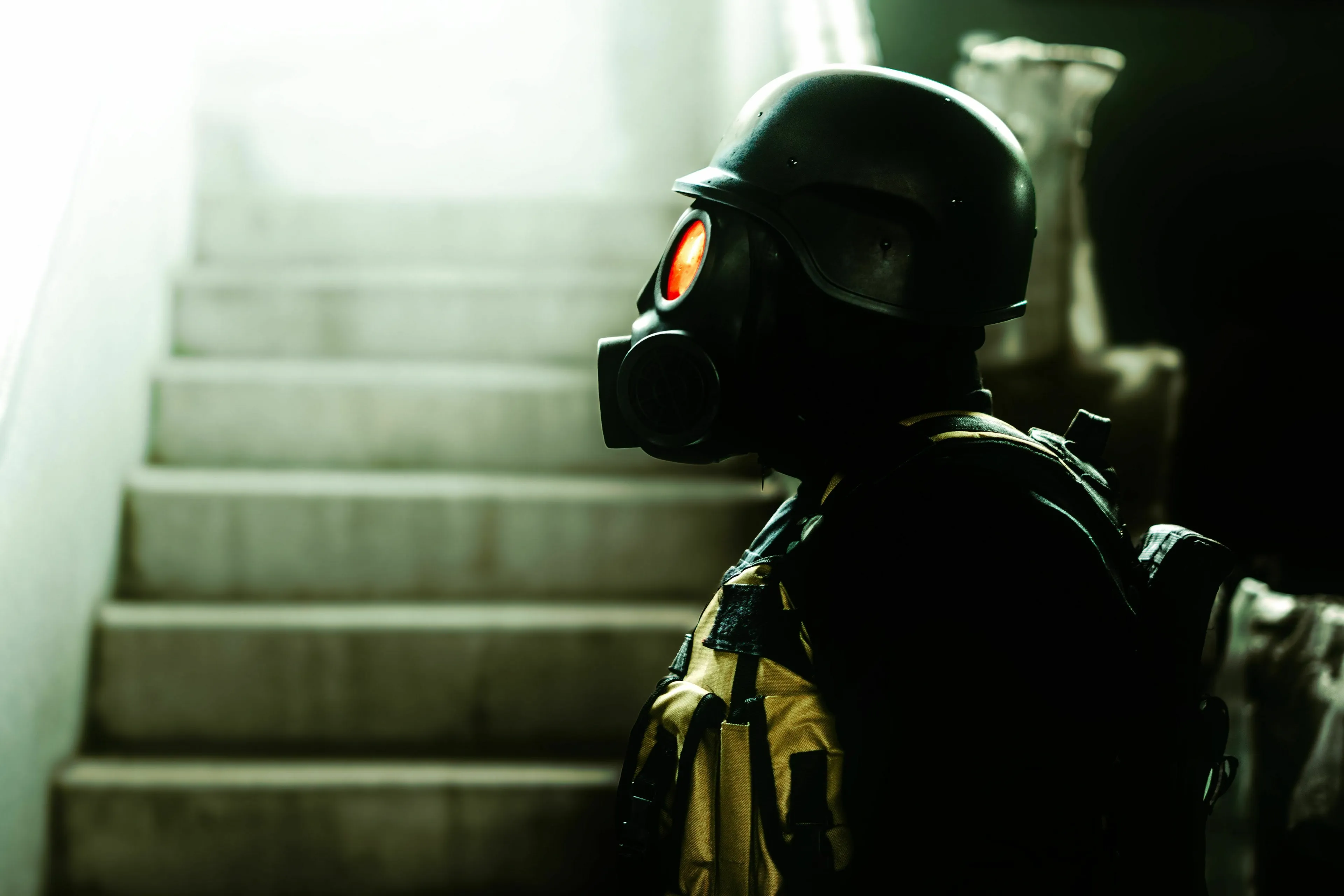 Which apocalyptic scenarios sounds least alarming, a person in a gas mask and helmet looking up a flight of stairs.