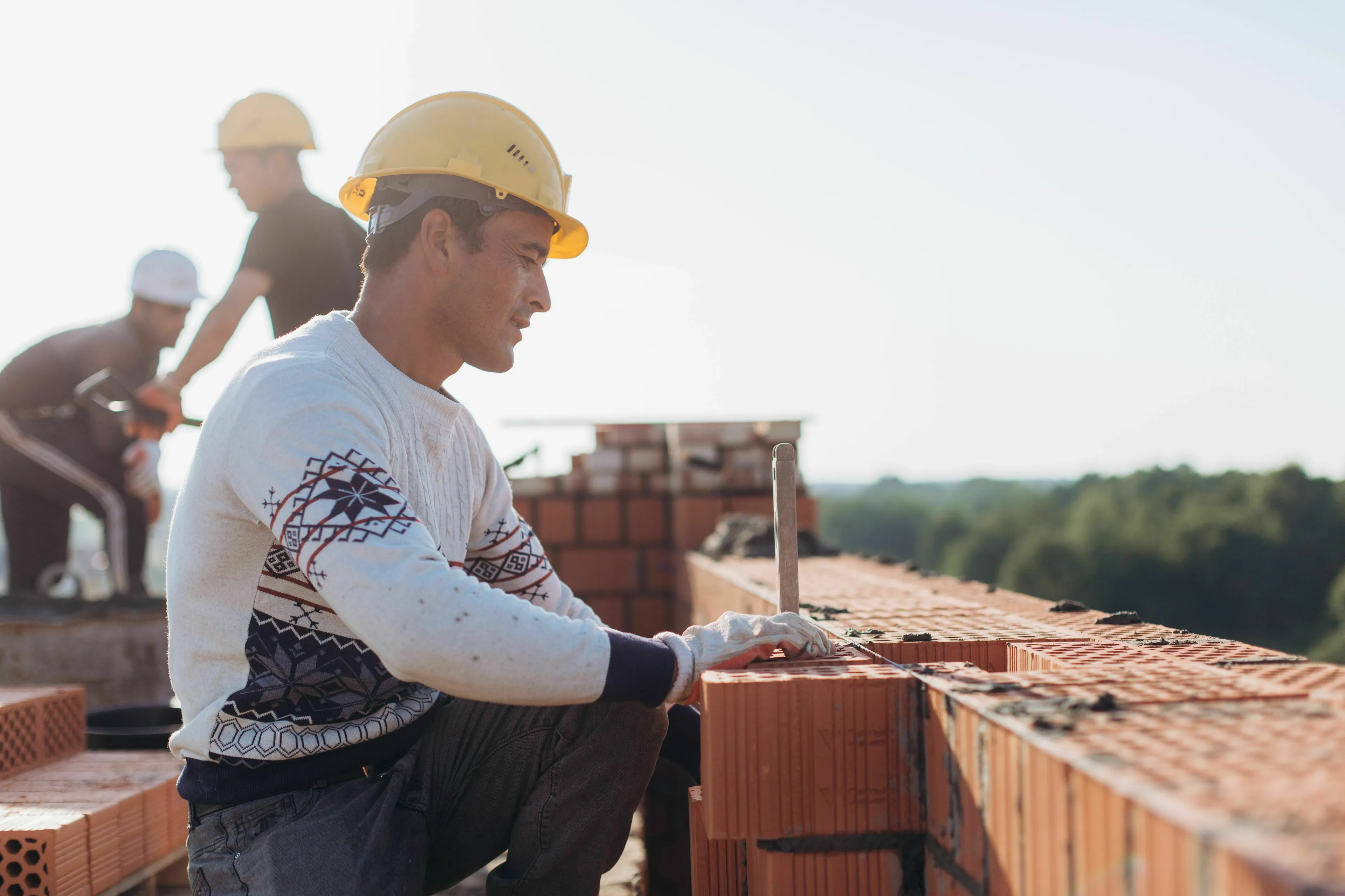 Construction worker in a hard hat laying bricks, a solution for skilled labor shortage.