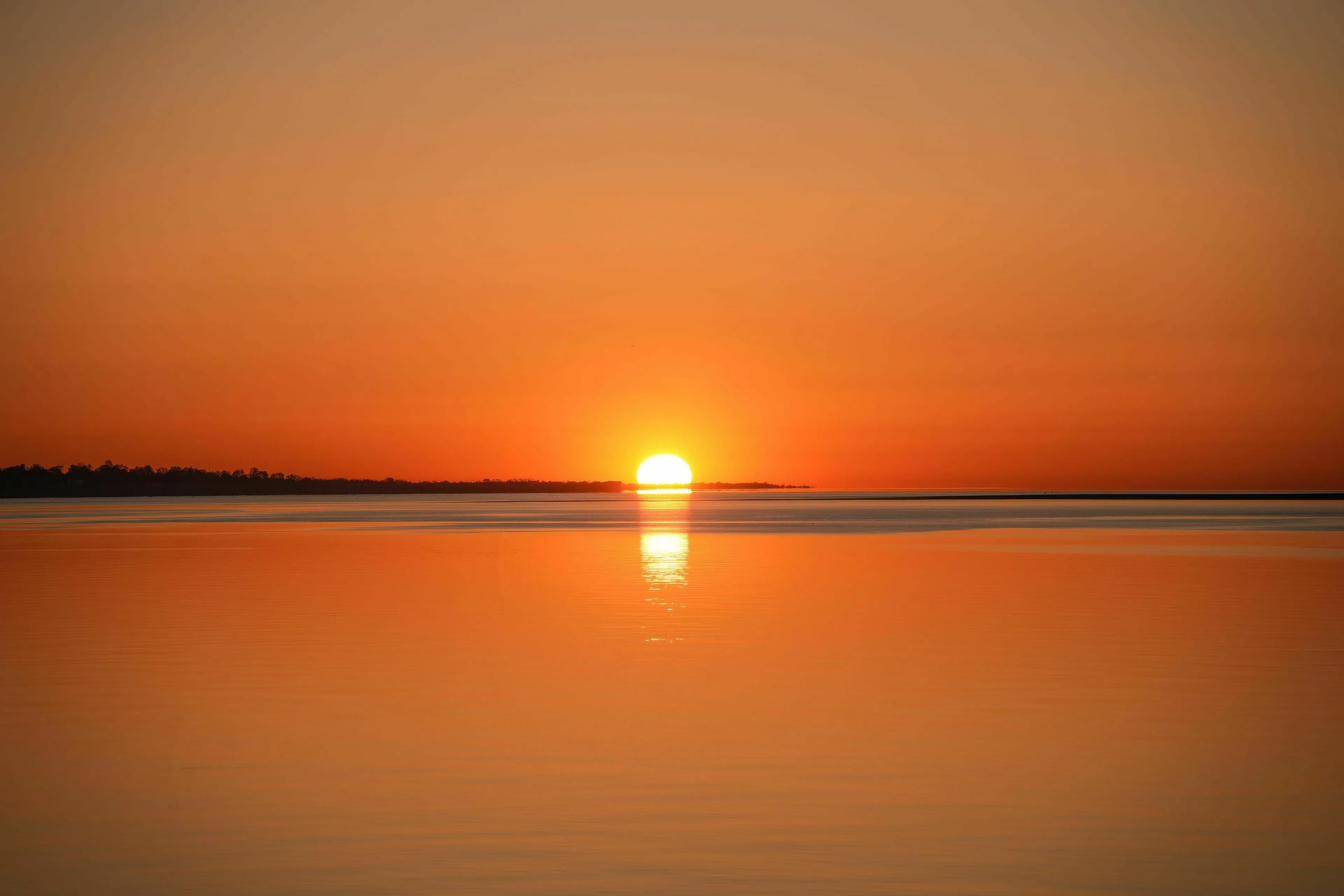 A beautiful golden sunrise over calm water, an unexpected free morning in a utopia or dystopia.