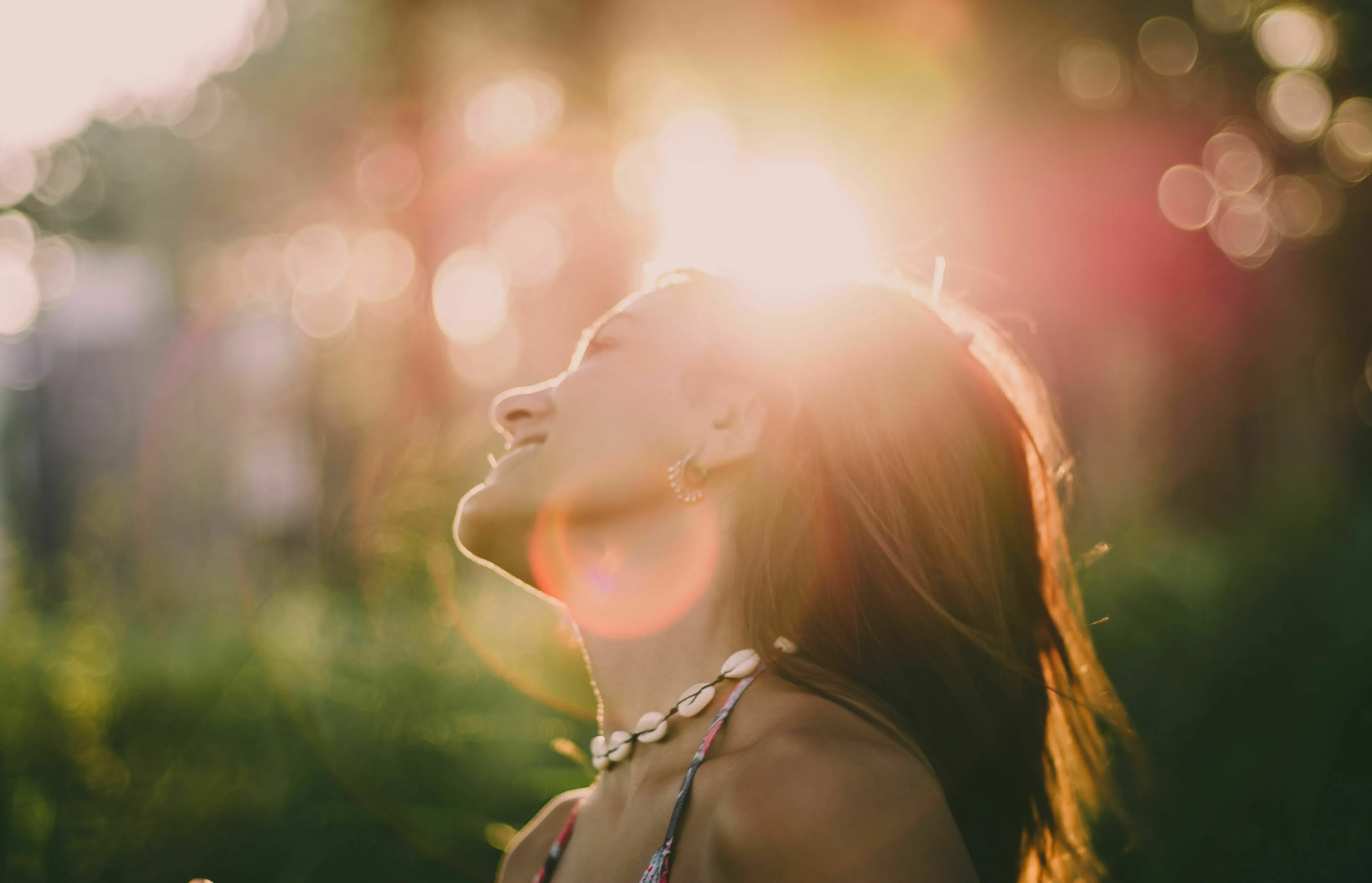 A woman smiling with her face towards the sun, imagining herself truly thriving in a utopia or dystopia.