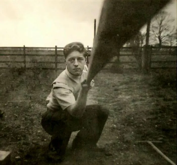 Man kneeling outdoors, holding an object, a historical photo that is interesting.