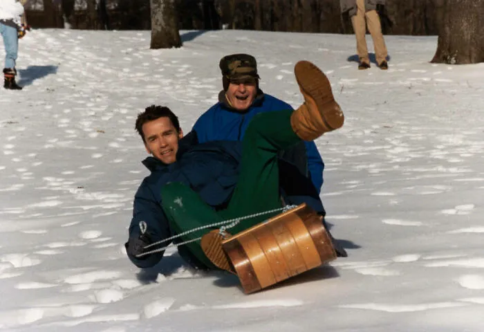 A candid, interesting photo from history of two men sledding in snow, smiling.