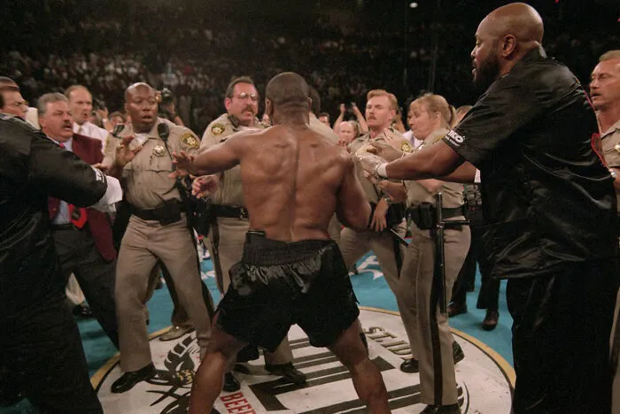 An interesting, heartbreaking photo from history of a boxer being restrained by security guards in a ring.