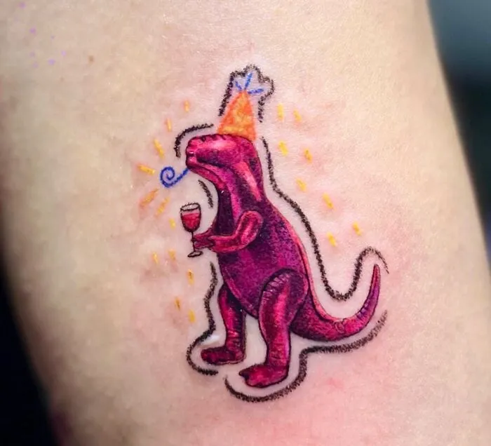 Vibrant crayon drawing-inspired tattoo of a purple dinosaur with a party hat and a drink, reflecting childhood creativity.