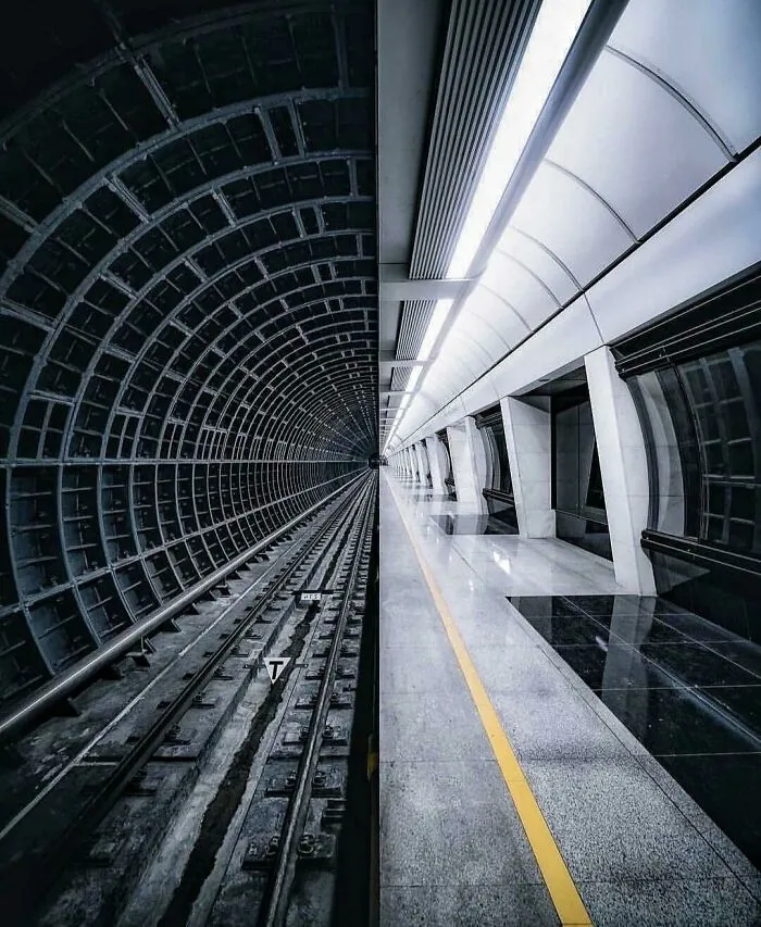 A fascinating find: a split image showing a dark subway tunnel on one side and a brightly lit station on the other.