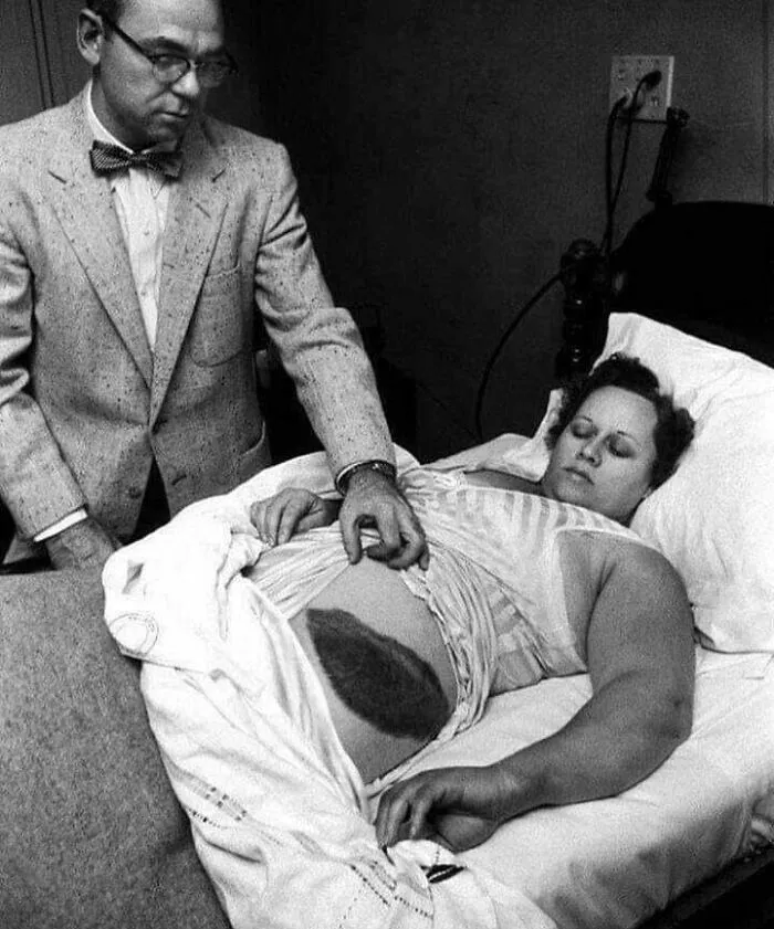 A black and white image of a doctor touching a woman's pregnant belly, showcasing a fascinating find on the internet.